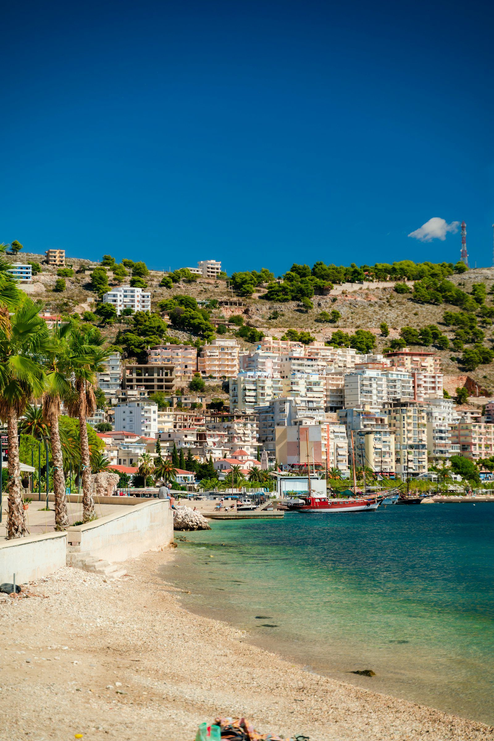 Albanian coastal town seen across the bay, where seaside venues price differently from Tirana in peak season