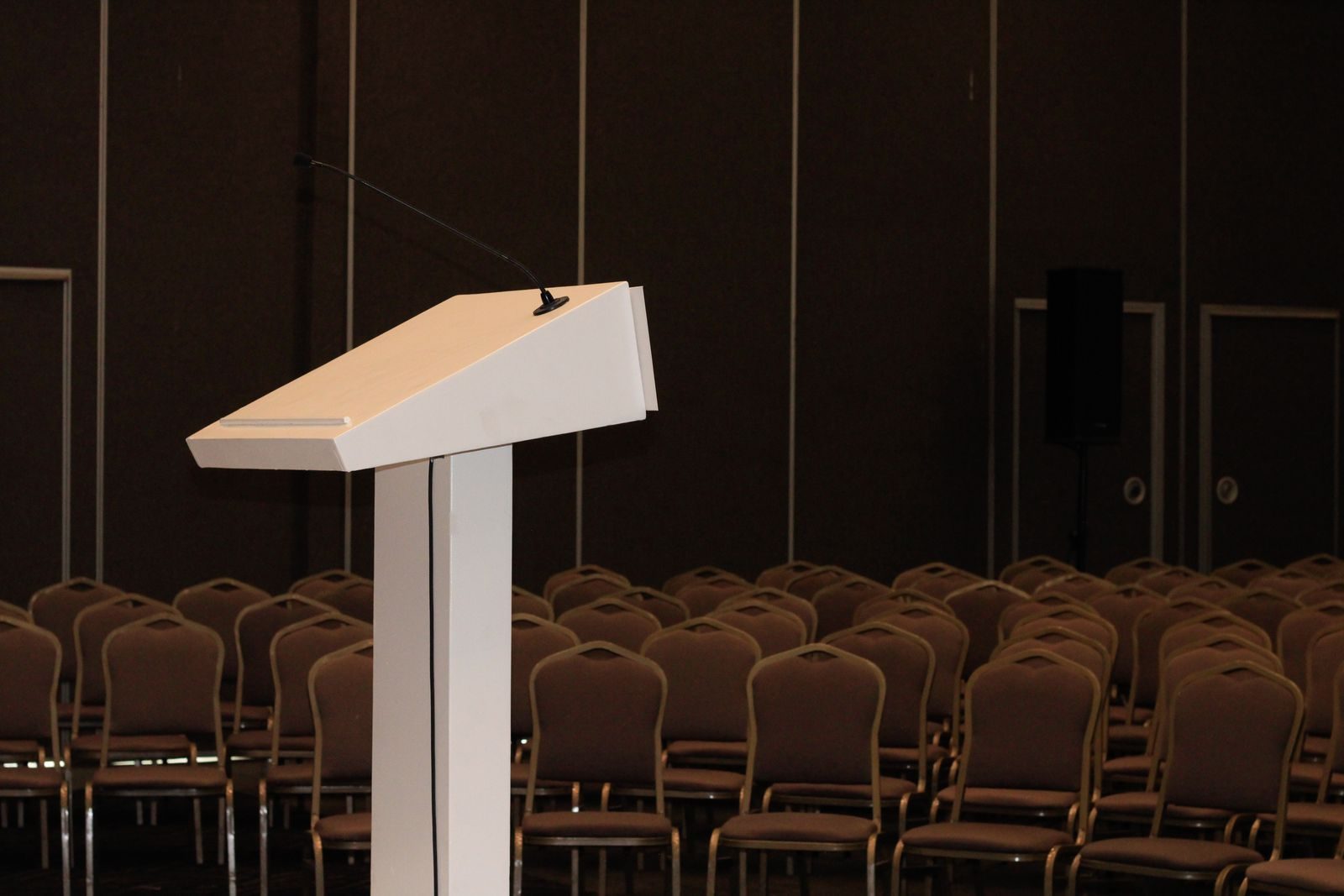 Rows of chairs facing a podium in an empty conference room set for a plenary session
